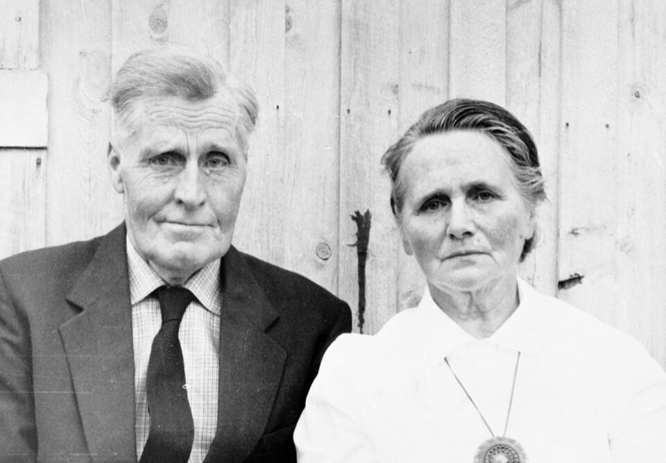 Før: svart-hvitt-bilde av et eldre ektepar foran en trevegg, tatt i 1965.